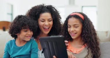 Anne, çocuklar ve evde eğitim için tablet, e-öğrenim ve kanepe üzerinde komik video veya film yayınları olan online oyunlar. Okul web sitesi için dijital teknolojide mutlu ırklar arası aileler ve çocuklar.