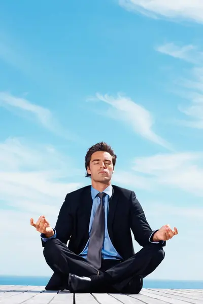 Meditation, thinking and business man on blue sky for relaxing, positive mindset and solution. Corporate person, professional and worker outdoors in yoga pose for wellness in career, work and job.