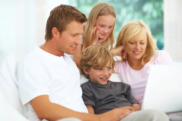 Laptop, video or streaming with a family on a sofa in the living room of their home together for entertainment. Parents, children or computer for subscription service with a mother, father and kids.