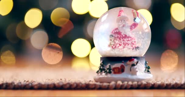 クリスマス 雪のグローブ またはお祝いのためのテーブルの上の装飾 ボケで自宅で与えるか アパートのギフトとして白いXmas 党またはブリザードのボールのためのサンタの句 冬またはお土産 — ストック動画