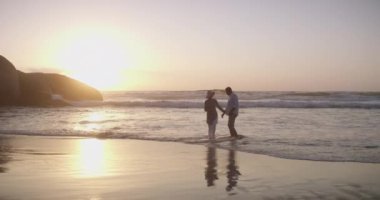 Olgun bir çift, kumsalda yürüyor ve gün batımında el ele tutuşuyorlar ve tatilde, dışarıda ve mutlu bir şekilde evleniyorlar. Emeklilik, yaşlılık ya da bağlılık sevgisi, bağlılık ya da romantik bir ilişki..