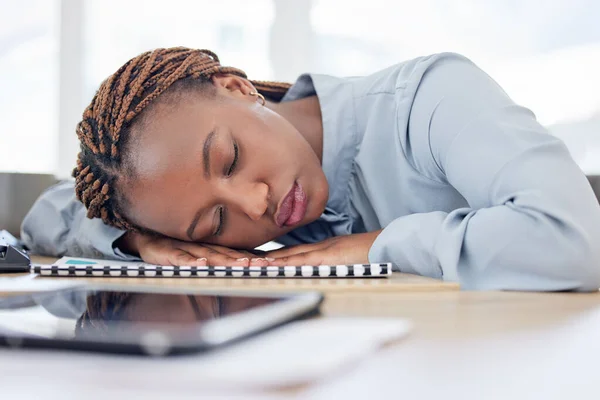 African woman, tired and sleeping on office table with rest, burnout and nap for overtime, project and documentation. Employee, person and eyes closed for exhausted, fatigue and dream in workplace.