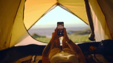Kamp, telefon ve kadın yaz macerası, tatil ve açık hava tatili için çadırda. Yürüyüş, fotoğrafçılık ve sosyal medya için akıllı telefondaki kişi, çevrimiçi paylaşım ve kamp alanında seyahat blogu.