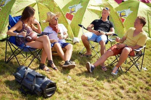 Camping, group of friends in conversation at tent and relax with outdoor chat, drinks and grass. Nature, men and woman at campsite together for music festival, adventure and people bonding in park
