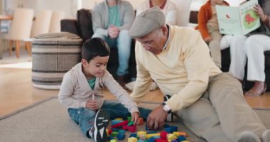 Aile, yapı taşları ve ev ziyareti sırasında torunuyla oturma odasında oynayan bir büyükbaba. Çocuklar, yaşlı bir adamla oyuncaklarla sevin ya da öğrenin. Torunuyla yerde kaynaşın..