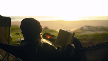 Kadın, kitap okuyup kamp yapıyor ateşin yanında seyahat ediyor ve sabahları seyahate çıkıyor. Sakin, rahat ve okyanus maceralı ve açık havada deniz kenarında güneş doğuyor ve doğada özgürlük var..