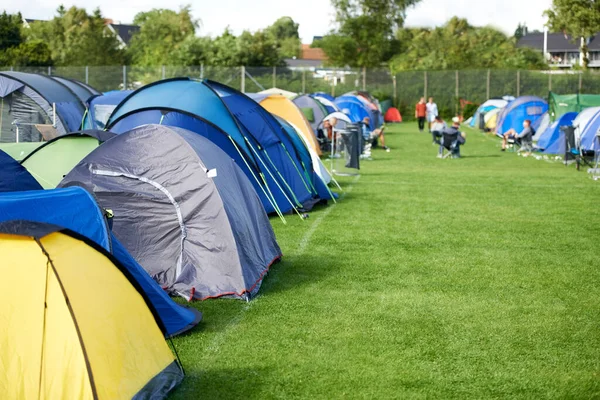 Camping, tents and outdoor music festival in park with people on field with grass or trees in summer. Camp, site and shelter at party, event or travel in woods for concert, adventure and carnival.