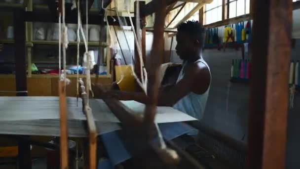 衣料品工場 職人技でのマン フロアトリードル織物 ファブリック生産 黒人の男性 倉庫および編む糸か綿の企業 ウールおよび織物のデザイナー — ストック動画