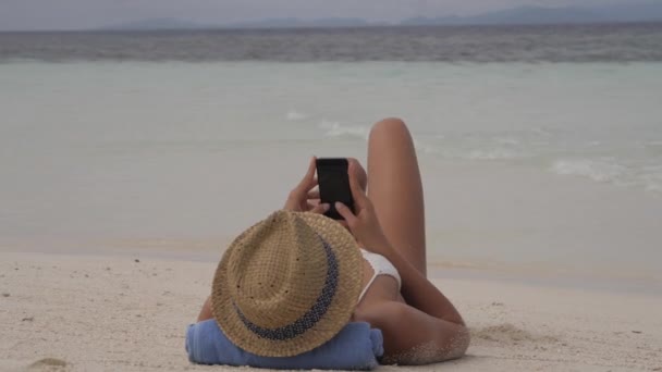여자는 미디어와 휴식을 취하고 파도와 바다에 게시물을 입력합니다 인도네시아의 모래에 — 비디오