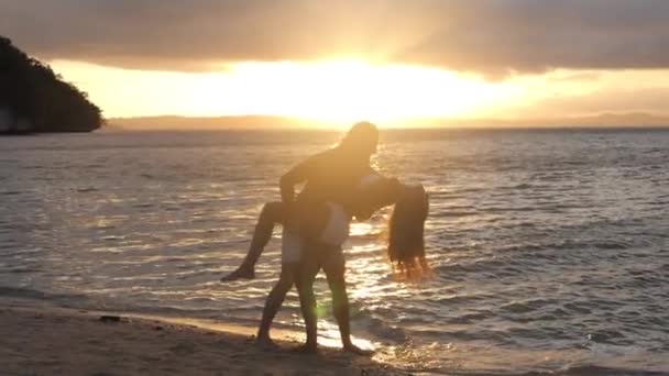 夕阳西下 沙滩和情侣们在大自然中跳舞 带着爱 拥抱或庆祝 结合在一起 或在户外玩乐 自由和人们在海洋中享受日出 探险或带着镜头闪闪的浪漫生活 — 图库视频影像
