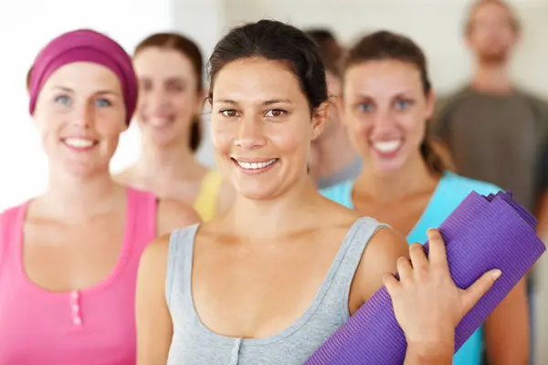 Portrait, yoga or fitness and a group of women in a studio for health, wellness or mindfulness. Exercise, workout and pilates with happy young friends in gym class together for holistic training.
