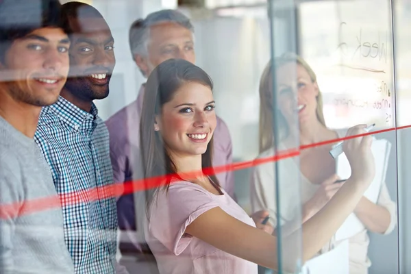 Happy woman, team and writing on glass board for schedule planning, meeting or creative strategy at office. Portrait of employee group smile in teamwork, collaboration or startup project at workplace.