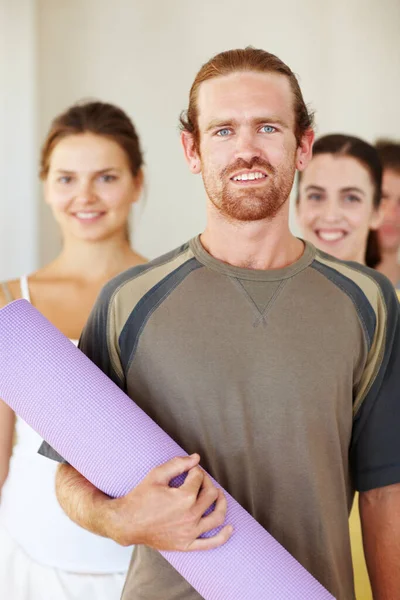Portrait, yoga or exercise mat and man with a group of people in a studio for health, wellness or mindfulness. Fitness, training and pilates with happy young friends in gym class for holistic balance.