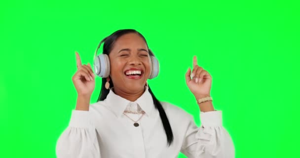 スタジオの背景を背景に 緑の画面で音楽を聴いて笑っている幸せな女性 ヘッドフォン ダンスや幸福のオーディオストリーミングやオンラインサウンドトラックを楽しんでヘッドセットを持つ女性 — ストック動画