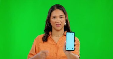 Hayal kırıklığına uğramış Asyalı kadın, telefon ve model yeşil ekranda başarısız ya da kafası karışmış bir şekilde stüdyo arka planında. Cep telefonlu rahatsız kadın portresi görüntüleme ve izleme işaretleri oluşturur.