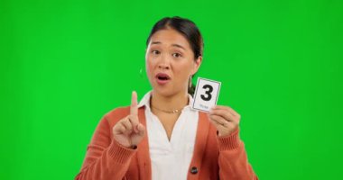 Asyalı bir kadın. Stüdyo geçmişine karşı yeşil ekrana güvendiği için öğretmenlik yapıyor. Öğrenme ya da eğitim için sayıyı ve parmak sayısını açıklayan mutlu kadın ya da öğretmen portresi.