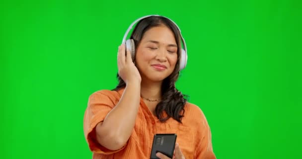 收音机耳机和女人在工作室的绿色屏幕上被隔离在一个背景模型中 倾听和快乐的亚洲人流淌着声音 声音或播客 爵士乐和跳嘻哈舞 — 图库视频影像