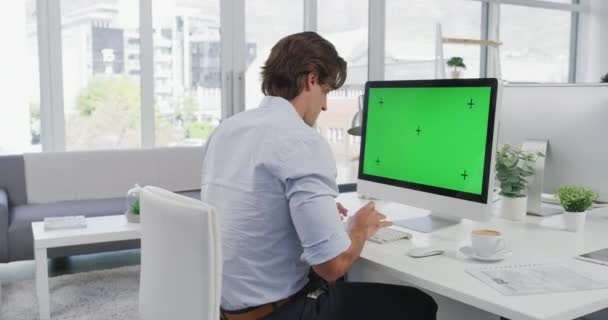 リラックスした コンピュータと緑の画面を持つ男 クロマキーの同僚のスペースと思考とモックアップ デザイン代理店で働くビジネスマン ウェブサイトのためのデスクトップ上の技術のモックアップとトラッキングマーカー — ストック動画