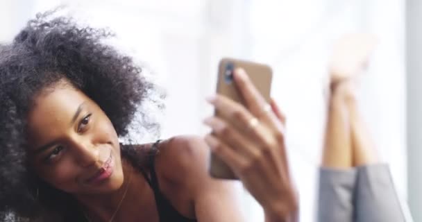 自撮り リラックスして幸せな黒人女性がソーシャルメディアの投稿 影響力のあるブログのためにベッドにいます ネットワーキング ベッドルーム 女性の笑顔は自宅でモバイルアプリ インターネットやウェブサイトのための写真を撮る — ストック動画