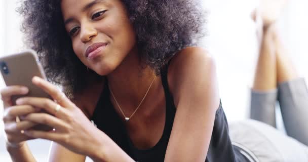 ベッドのテキストメッセージを入力し チャットやソーシャルメディアの投稿を読む上でリラックスし 幸せな黒人女性 自宅でモバイルアプリ インターネットやウェブサイトのためのスマートフォン上のネットワーキング ベッドルームや女性の人 — ストック動画
