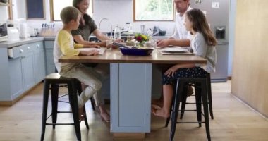 Mutlu aile, evde yemek ve sohbet anne, baba ve çocuklarla birlikte mutfakta yemek yemek için. Öğle yemeği, anne ve baba evdeki yemek masasında kaliteli zaman geçirmek için çocuklarla konuşuyor..