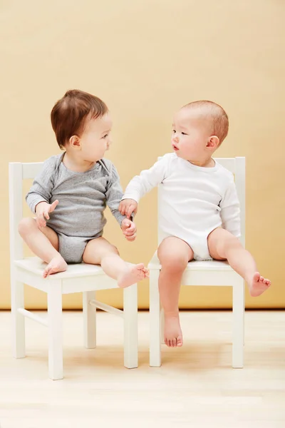 椅子和男婴在橙色背景的工作室里成长或发展 年轻的 可爱的 可爱的 兄弟姐妹的或年幼的幼儿坐在一起与家人团聚 — 图库照片