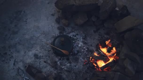 ロック アウトドア キャンプファイヤー または場所で夜に鍋で調理 南アフリカの食糧 栄養または食事と鉄の容器 炎そして上を鋳造して下さい — ストック動画
