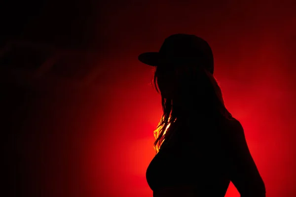 Woman, red light and silhouette at party concert or festival night, stage event or dark. Female person, strobe and glow for artistic creative shadow for dance rave, entertainment or mockup background.
