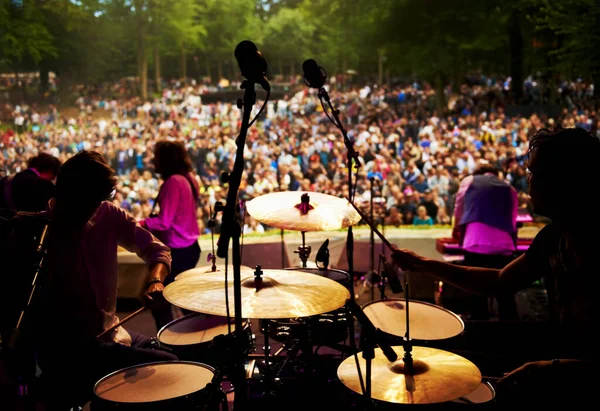 Band, concert and stage in outdoors, party and event or energy for freedom on vacation. People, drums and music festival or rave, audio and song for fun crowd and musicians with instruments for show.