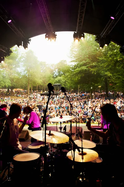 Band, concert and stage in outdoors, event and party or energy for freedom on vacation. People, drums and music festival or rave, audio and song for fun crowd and musicians with instruments for show.