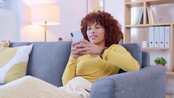 非洲裔美国女人一边在网上聊天一边在一个约会应用程序上笑 快乐的黑人女性坐在沙发上 一边打电话一边发短信 在社交媒体上阅读有趣的迷因或上传的女士 — 图库视频影像