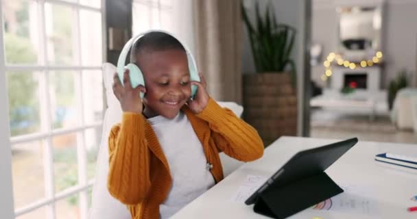 ヘッドフォン タブレット 男の子は ダイニングルームでオンラインで音楽 プレイリスト またはアルバムに踊ります デジタルテクノロジー アフリカの子供たちが 現代の家庭で歌やラジオを聴きながら移動する — ストック動画