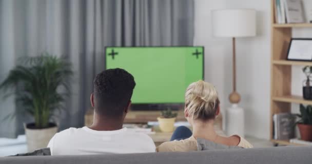 カップル 自宅でリビングルームのソファで一緒に映画のためのテレビや緑の画面ストリーミングエンターテイメントを見て 男と女リラックス上のラウンジソファテレビによってChromakey表示またはMokup — ストック動画