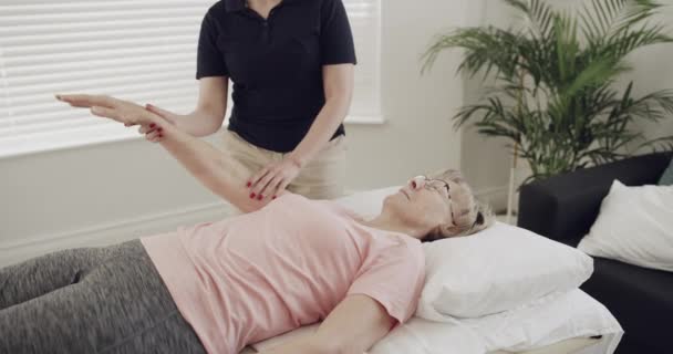 女性患者 理学療法士やリハビリテーションや理学療法のための腕を伸ばし 理学療法と健康療法のためのカイロプラクターを持つシニア人 — ストック動画