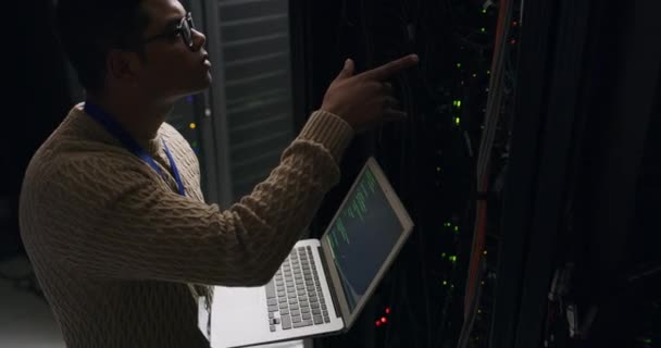 ラップトップ コーディング サイバーセキュリティ ネットワーク管理 デジタルストレージのエンジニアを持つデータセンターの男 暗いサーバールームで技術者 従業員 システムメンテナンスや技術者をコードする — ストック動画