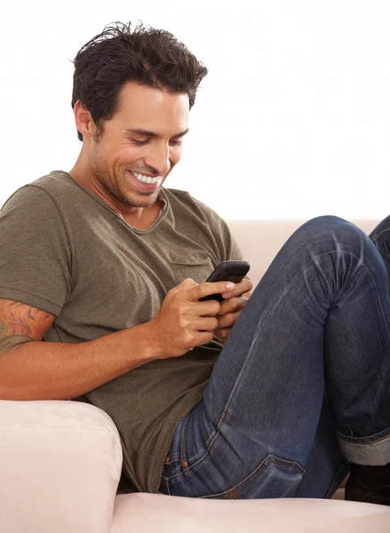 Man, phone or happy on sofa with relax, communication or conversation for break in living room of home. Person, face or smile with smartphone or technology on couch in lounge for text message or chat.