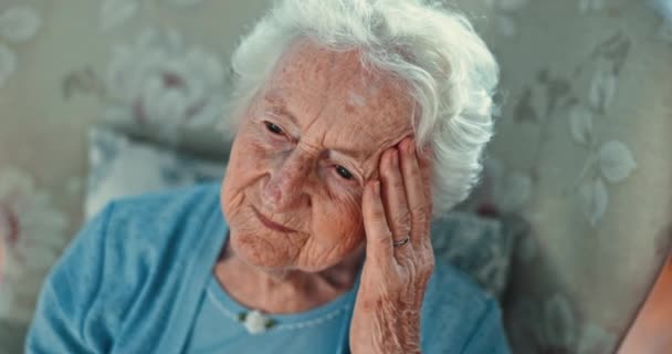 头疼和老年妇女坐在椅子上 有记忆力丧失 恐惧或怀疑 担心或过度思考 疗养院中的焦虑 偏头痛和老年女性 因后悔 失落或被遗弃 — 图库视频影像