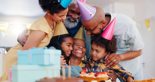 Happy black family, birthday and bonding in celebration for party, holiday or special day together at home. Excited African grandma smile with hug in unity, love or care for event, cake and candles.