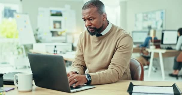 成熟的黑人男子和在办公室的笔记本电脑上打字更新网络 在线评论和数字报告 从事计算机研究 规划或代理信息工作的认真的企业家 — 图库视频影像