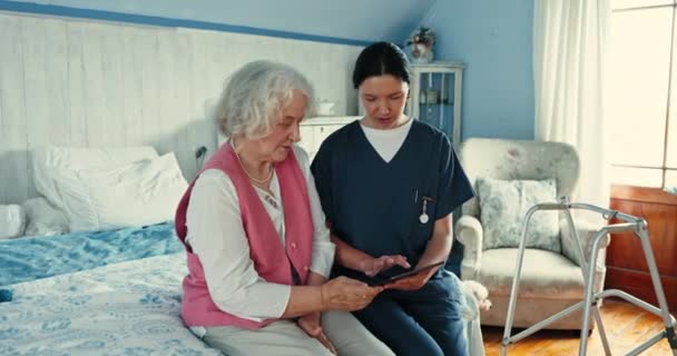タブレット 看護師とシニアの女性と退職後の家庭の寝室での相談 デジタルテクノロジー 女性介護者は 自宅で診断のために高齢の患者と話しています — ストック動画