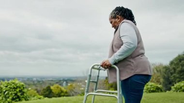 Siyahi bir kadın, yaşlı, yürüme ve emekliliği olan, açık bahçede temiz hava alan ve doğada dinlenen. Çevre, engelli ve rehabilitasyonu olan kişi, kırsal kesimde yaşlı bakımı ve görüşü.