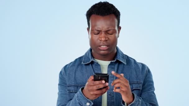 携帯電話でスタジオにいる黒人男性と コネクションのグリッチで読書ポスト メッセージ 通知をイライラさせました ストレス 混乱した人 スマートフォン エラー スパムメール ブルーバックグラウンド — ストック動画