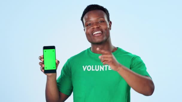 ウェブサイトのプレゼンテーションのための男 ボランティア 電話グリーン画面 私たちに参加するか スタジオでボランティアにサインアップします 青い背景にモバイルアプリやビデオスペースを搭載したアフリカ人またはNgoスピーカーの顔 — ストック動画