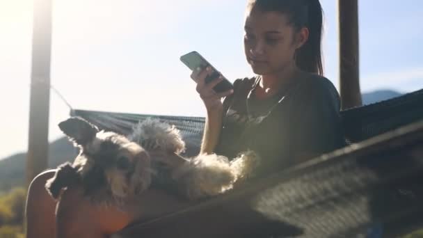 狗和放松在吊床上 户外和电话发短信 联系或在网上聊天 在度假 度假和乡村的女孩 小狗或动物宠物 用智能手机进行社交媒体应用 — 图库视频影像