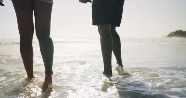アドベンチャー 愛のために屋外でリラックスするためのビーチでカップル ウォーキング 波の人々の足 休日のための海と海 夏休みと週末 — ストック動画