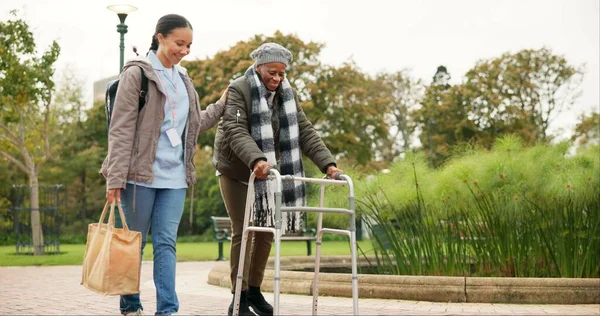 Nurse, support and walker with old woman in park for helping, person with a disability and retirement. Elderly care, nursing and rehabilitation with caregiver and patient in nature for healthcare.