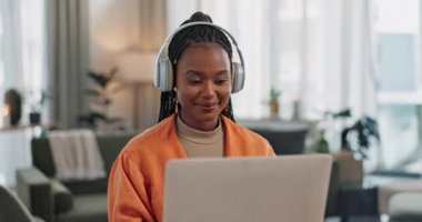 Laptop, kulaklıklar ve genç bir kadın modern dairede müzik, müzik listesi ya da albüm dinliyor. Teknoloji, gülümseme ve evdeki dinlenme odasında bilgisayar başında şarkı söyleyen genç Afrikalı.