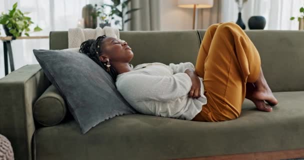 痛苦和黑人妇女在沙发上 抽筋和胃与疾病 痛苦和疾病在客厅里 有腹部问题 肚子痛和月经期的非洲人 公寓和女孩 — 图库视频影像