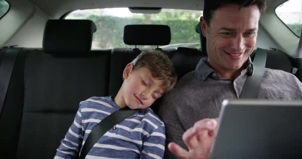 爸爸和孩子一起开车带着平板电脑 一起看视频或网络游戏 数字应用和父亲与男孩坐在出租车 互联网和交通的后座上 在旅途中放松一下 — 图库视频影像