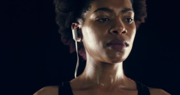 听音乐 呼吸锻炼 训练或在工作室锻炼 带耳机 体育播客的非洲运动员在镜头照明弹中对黑色背景的思考 — 图库视频影像